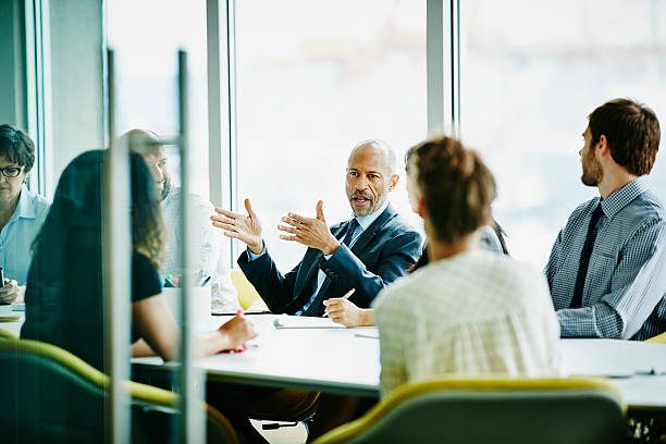 Business leader engaging in a strategic discussion with a diverse team in a modern office setting, illustrating leadership and consulting dynamics.