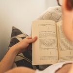 Woman enjoying relaxation by reading a book on a cozy couch indoors.